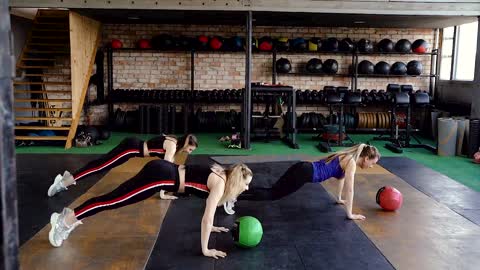 Three Women Working Out In A Gym Using A Medicine Ball