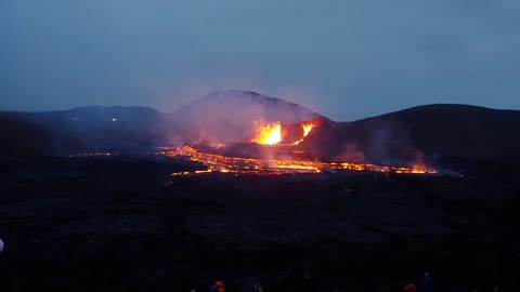 Lava Filmed Shooting Out of a Volcano as It Flows Down While People Talk in the Background