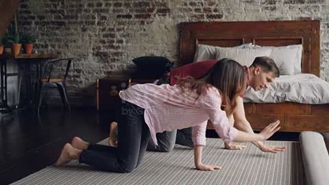 Young married couple is rolling out beautiful new carpet