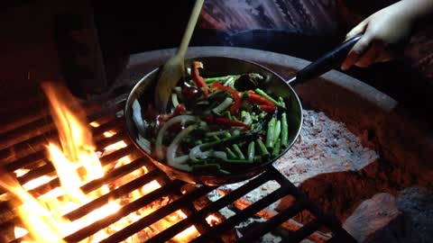 Camping at Topanga beach. Chelsea is sautéing some vegetables.