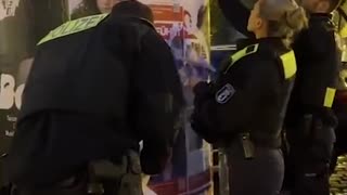 Police in socialist Germany is seen removing posters of Israeli hostages