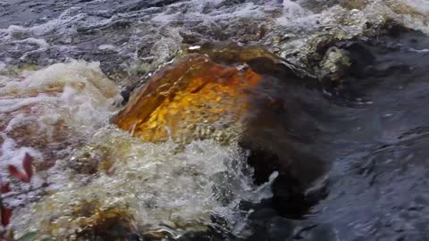 Amazing rust coloured water rushing up over a rock near Dumfries