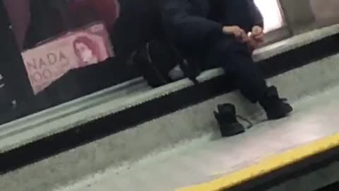 Man in black outfit clipping toe nails waiting for train