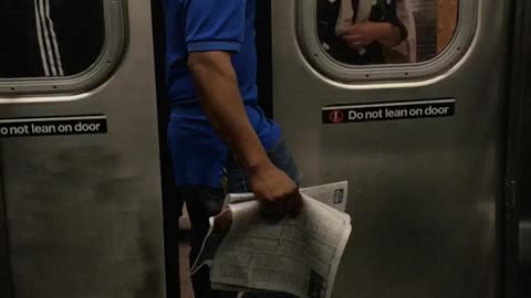 Man in a blue shirt standing between train doors