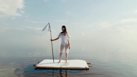 A Woman Holding a White Flag while Standing on the Raft