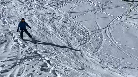 Skier skis down slope, flies off a ramp and falls