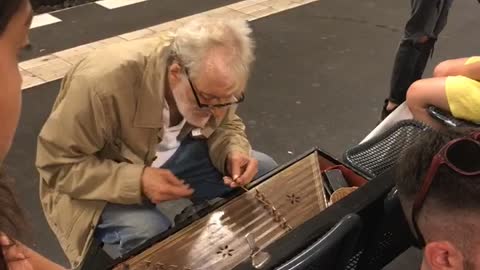 Old guy subway playing wooden string instrument