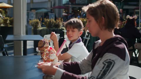 The kids are sitting in the restaurant eating ice cream