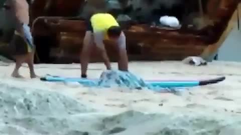 Guy yellow shirt kicking sand out of the way at beach