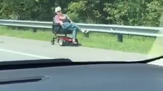 Woman on red scooter drives down highway