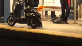 Man walking through train subway station with moped scooter bike