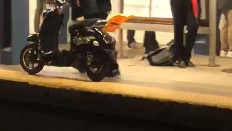 Man walking through train subway station with moped scooter bike