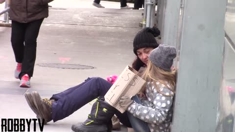 Young Homeless Girl Sits Alone Begging For Help. Pay Close Attention To Woman In Red Plaid