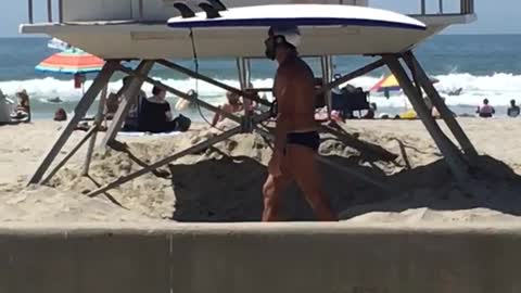 Music white helmet guy carries surfboard on head on beach