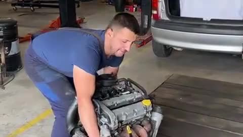 A mechanic installs a car engine