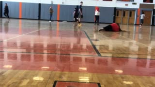 Girl kicks ball inside of gym, trips over her feet and falls hard