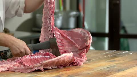 hands of butcher chopping lamb carcass