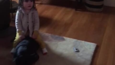 Kid watches sesame street and sits on black dog