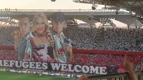 Legia Warsaw banner reading Refugees Welcome with girl with a pigs head on a plate
