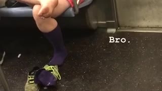 A woman in pink with her bare foot out on subway train