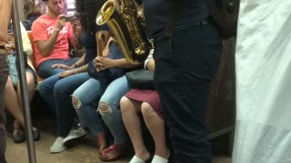 Guy green backpack playing saxophone on subway train