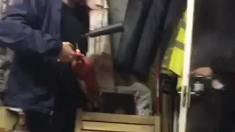 Man in blue uses fire extinguisher on man who walks in