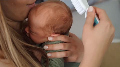 Mother brushing baby's hair, close up video of a baby