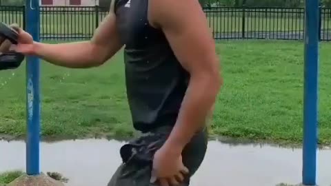 Stupid workout man doing pull up over rainwater