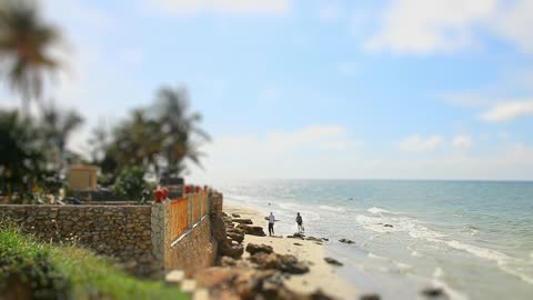 Tilt shift of people walking on windy beach