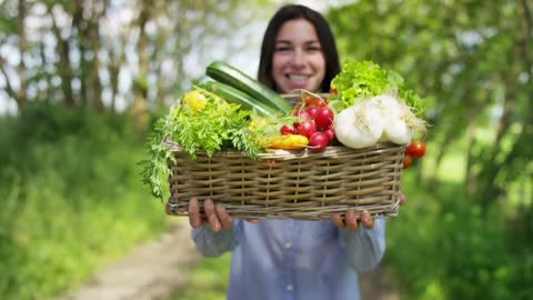 beautiful young girl holding a basket of vegetables in the background of nature con free stock video
