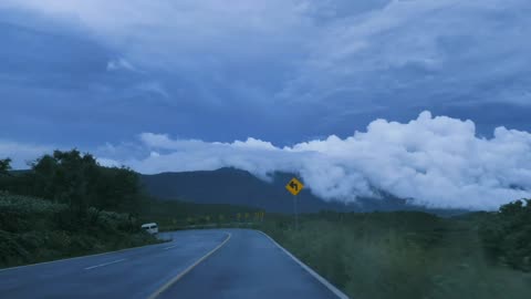 Going down a curved highway through a mountain range Point