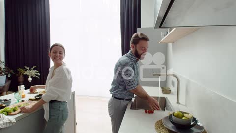 Laughing Couple Preparing Lunch Together In A Modern Kitchen