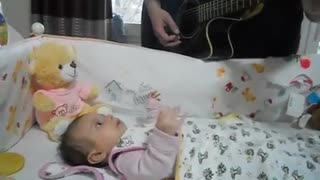 Beba cautivada por su papá mientras toca la guitarra