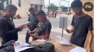 Migrants open their government issued cell phones after being processed in Brownsville, Texas.