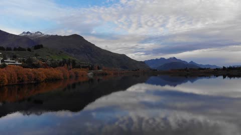 Beautiful Scenery of a Calm Lake Across the Mountains Under Cloudy Sky