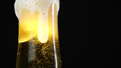 Glass of beer on a black background, in detail