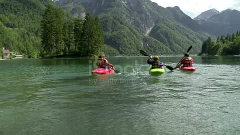 High angle shot of two parents with one child kayaking in the lake. Lago del Predel, Italy, Europe