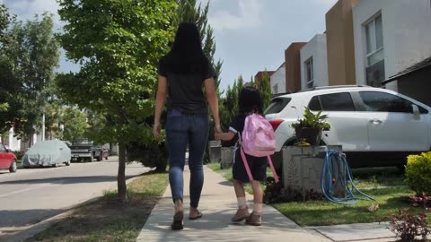 woman with her little daughter walking on the sidewalk