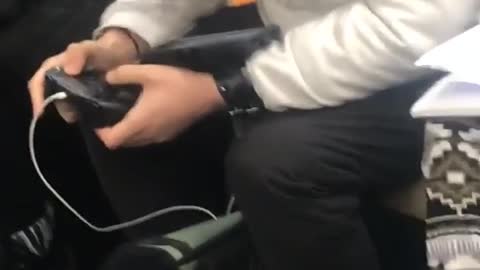 Guy uses controller to play portable game on subway train