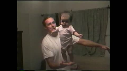 Father Balances Standing Baby Perfectly In One Hand