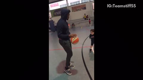 Man plays indoor basketball with toddler