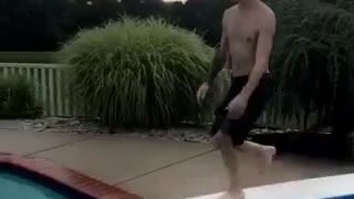 Guy in black swim trunks belly flops off diving board into pool