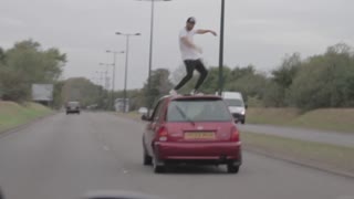 Dude dances on top of fast moving car on highway