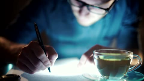 Man with insomnia writes with cup of tea