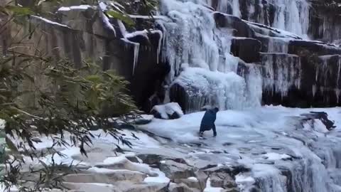 A person is photographing a frozen waterfall