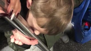 Little boy licking pole on subway