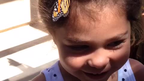 Monarch butterfly hangs out in little girl's hair