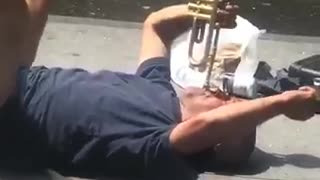 A man in blue playing trumpet on street floor