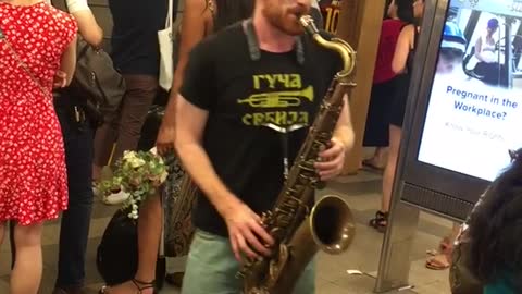 Guy black shirt shorts playing sorry not sorry in subway on saxophone