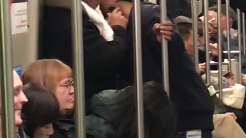 Guy helping other guy shave beard on subway